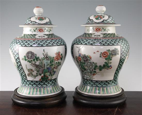 A pair of Chinese famille verte baluster vases and covers, late 19th century, 29.5cm, later drilled for lamp fittings, wood stands